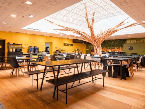 a restaurant with tables and chairs and a tree at ibis Styles Calais Centre in Calais