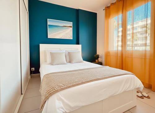 a bedroom with a white bed and a blue wall at Superbe T2 vue mer avec ascenseur 22 in Canet-en-Roussillon