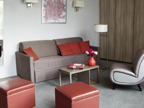 a living room with a couch and a table and a chair at Aparthotel Adagio Vienna City in Vienna