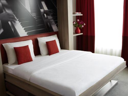 a bed with red pillows in a room at Aparthotel Adagio Vienna City in Vienna