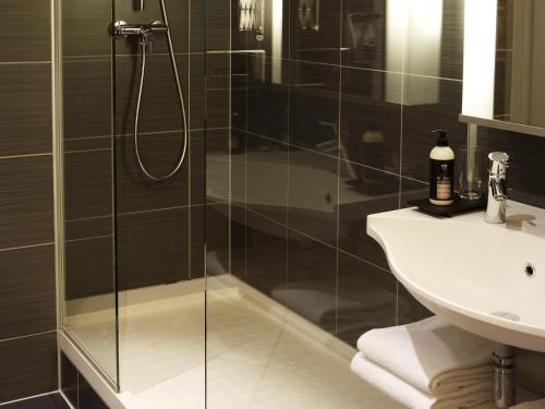 a bathroom with a glass shower and a sink at Aparthotel Adagio Vienna City in Vienna