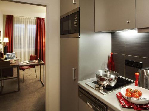 a kitchen with a stove top oven next to a table at Aparthotel Adagio Vienna City in Vienna