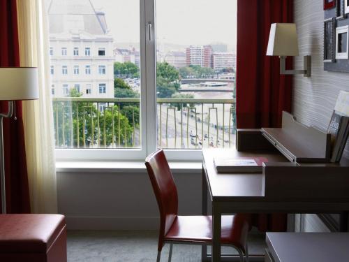 a room with a desk and a window with a view at Aparthotel Adagio Vienna City in Vienna