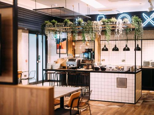 a restaurant with a counter with tables and chairs at ibis Belfast City Centre in Belfast