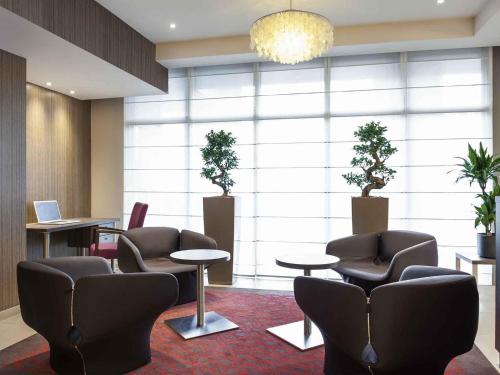 a waiting room with chairs and tables and plants at Mercure Hotel Brussels Centre Midi in Brussels