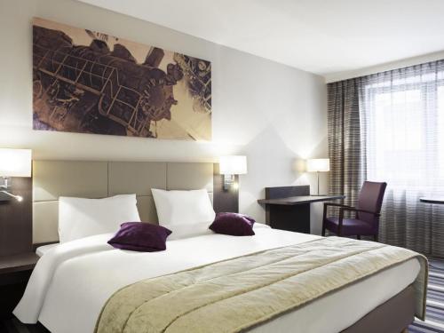 a hotel room with a large bed and a desk at Mercure Hotel Brussels Centre Midi in Brussels