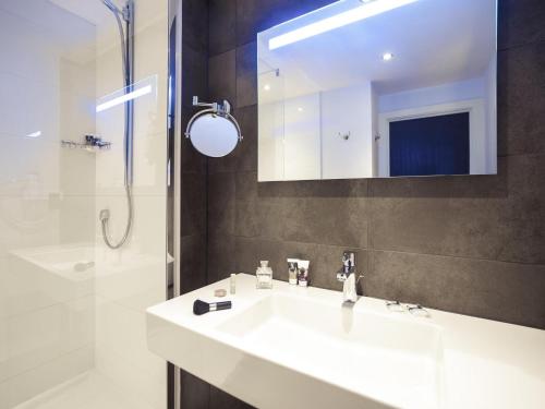a bathroom with a sink and a shower and a mirror at Mercure Hotel Brussels Centre Midi in Brussels