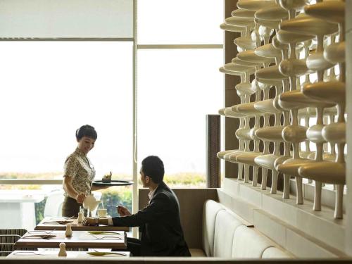 a couple of people sitting at a table in a restaurant at Novotel Tangerang in Tangerang
