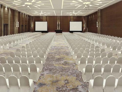 an empty hall with white chairs and two screens at Novotel Tangerang in Tangerang