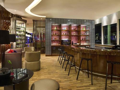 a bar in a restaurant with chairs and a counter at Novotel Tangerang in Tangerang