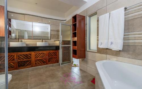 a bathroom with a tub and a sink at Villa Cashew Diani in Diani Beach