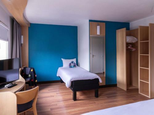 a bedroom with a bed and a blue wall at ibis Lille Lomme Centre in Lomme