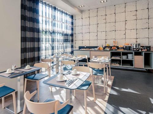 ティオンヴィルにあるHôtel Mercure Thionville Centre Porte du Luxembourgのテーブルと椅子とキッチンのあるレストラン