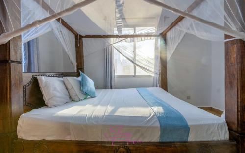 a bedroom with a large bed with a window at Villa Cashew Diani in Diani Beach