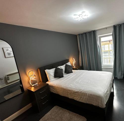 a bedroom with a bed with two lamps and a window at 2 Bedroom Flat Ground Floor Town Centre Colchester in Colchester