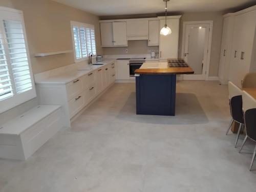 a large kitchen with white cabinets and a island at The Barn in Clonmel