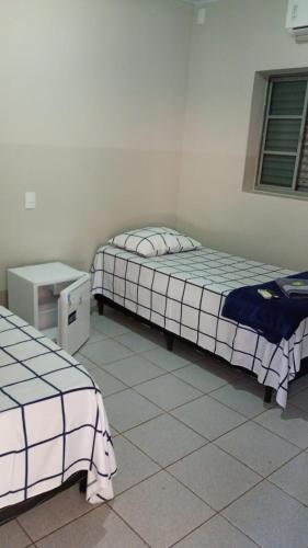 a room with two beds and a desk and a bed at Hotel Vale do Sol in Valparaíso