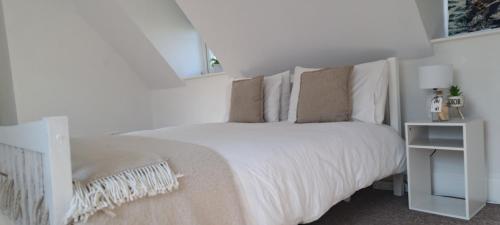 a white bedroom with a white bed and a night stand at Immense 6 bed with massive garden right on A1 in Holme