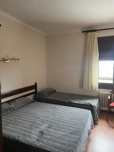 a bedroom with two beds and a window at Hostal Esplai in Viladamat