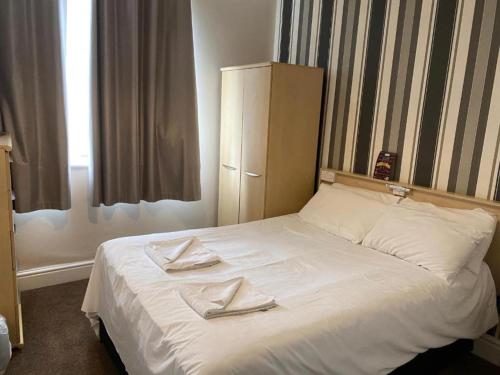 a bedroom with a white bed with two towels on it at The Arncliff Hotel in Blackpool