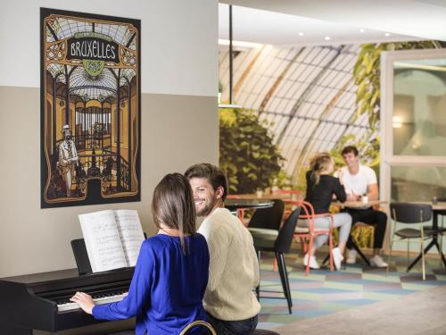 a man and woman sitting in front of a piano at Aparthotel Adagio Brussels Grand Place in Brussels