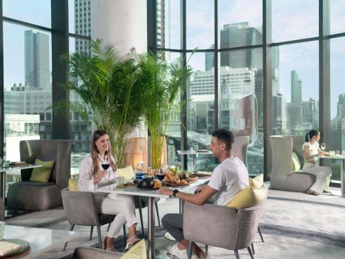 a man and woman sitting at a table in a restaurant at Novotel Bangkok Platinum Pratunam in Bangkok