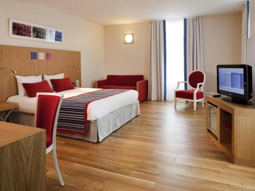 a hotel room with a bed and a flat screen tv at Hôtel Mercure Vittel in Vittel