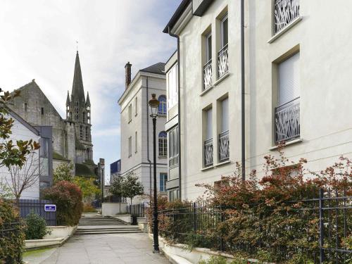 a street with white buildings and a church at ibis Etampes in Étampes