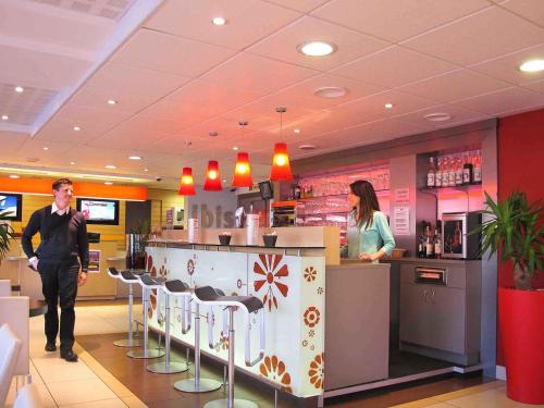 two people standing at a bar in a restaurant at ibis Etampes in Étampes
