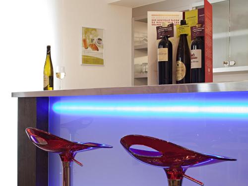 two red stools sitting under a counter with wine bottles at Hôtel Mercure Vittel in Vittel