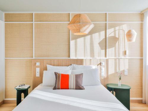 a bedroom with a large white bed with two tables at Mercure Président Biarritz Plage in Biarritz
