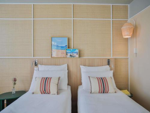 two beds in a hotel room with white pillows at Mercure Président Biarritz Plage in Biarritz