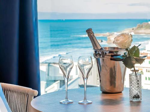 a table with two glasses and a bottle of champagne at Mercure Président Biarritz Plage in Biarritz