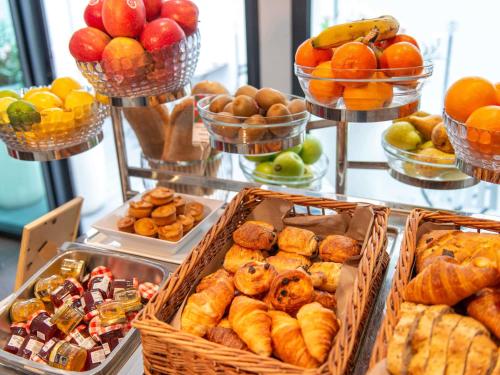 a buffet with baskets of different types of pastries and fruit at Mercure Président Biarritz Plage in Biarritz