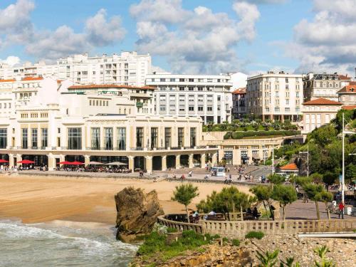 a group of buildings on a beach next to the ocean at Mercure Président Biarritz Plage in Biarritz