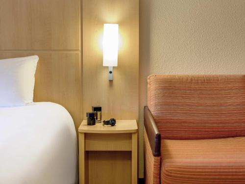 a bedroom with a bed and a table with a lamp at ibis Konstanz in Konstanz
