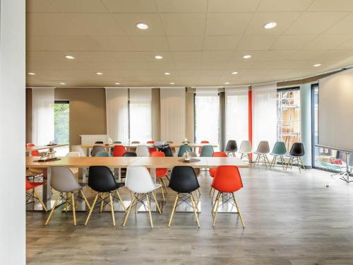 a conference room with tables and chairs and a screen at ibis Konstanz in Konstanz