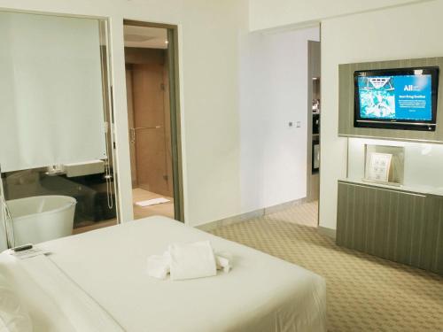 a hotel room with a bed and a television at Novotel Bangka Hotel & Convention Center in Pangkalpinang