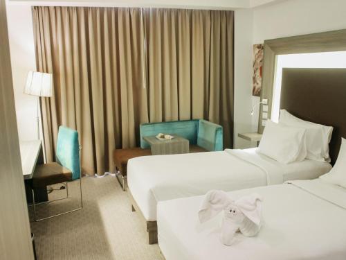 a hotel room with two beds with towels on them at Novotel Bangka Hotel & Convention Center in Pangkalpinang