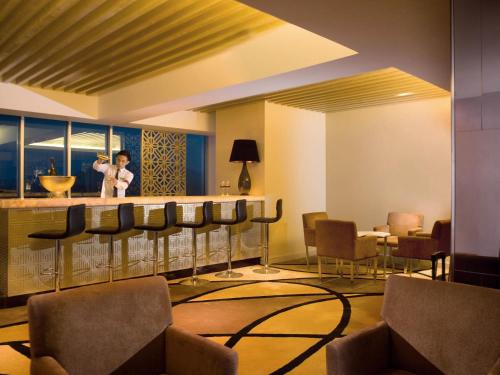 a lobby with a bar with chairs and a child standing at the counter at Novotel Bangka Hotel & Convention Center in Pangkalpinang