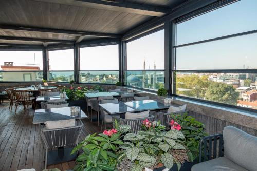 a restaurant with tables and chairs and large windows at Baver Hotel in Istanbul