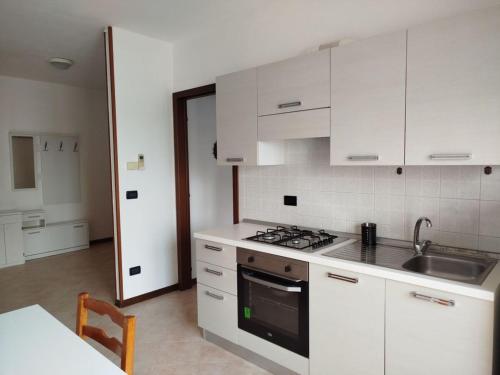 eine Küche mit weißen Schränken und einem Herd mit Backofen in der Unterkunft Cozy studio with pool in Caorle in Caorle