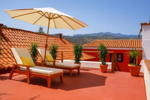 a patio with two chairs and an umbrella at Hotel Rural Villa del Monte in Santa Brígida