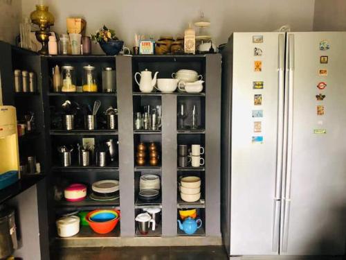 a cabinet with dishes and a refrigerator in a kitchen at Irishhome stay in Hosūr