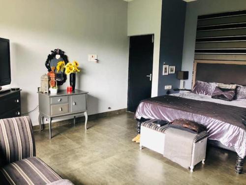 a bedroom with a bed and a table with a couch at Irishhome stay in Hosūr