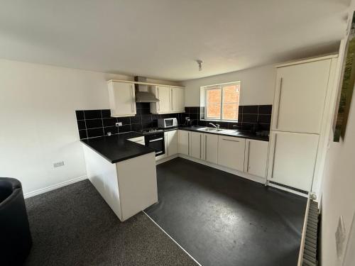 Una cocina con gabinetes blancos y una encimera negra. en Aylesbury, en Buckinghamshire