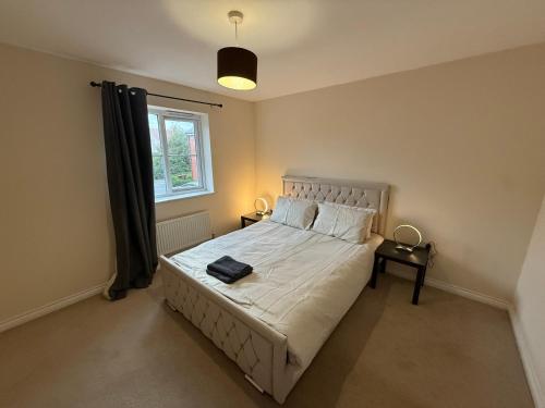 Un dormitorio con una cama grande con ventana. en Aylesbury, en Buckinghamshire