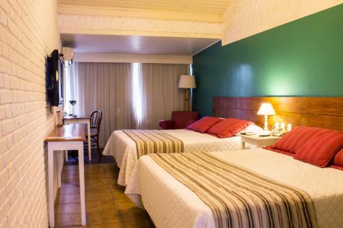 a hotel room with two beds and a table at Hotel Resort e Golfe Clube dos 500 in Guaratinguetá