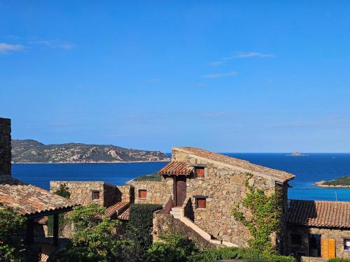 an old stone building with the ocean in the background at Villaggio Est a Capo Coda Cavallo San Teodoro in San Teodoro