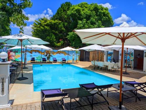 a swimming pool with chairs and umbrellas at Hôtel Les 12 Collines, Ivato Aéroport in Ambohijanahary